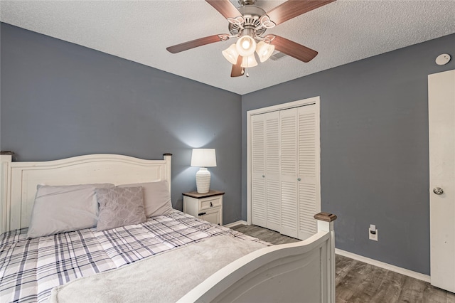 bedroom featuring a textured ceiling, wood finished floors, a closet, and baseboards