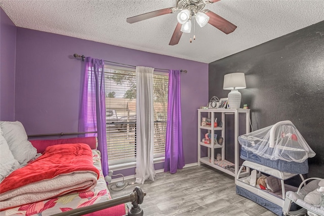 bedroom with ceiling fan, baseboards, a textured ceiling, and wood finished floors