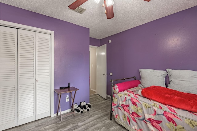 bedroom featuring a ceiling fan, a textured ceiling, wood finished floors, a closet, and baseboards