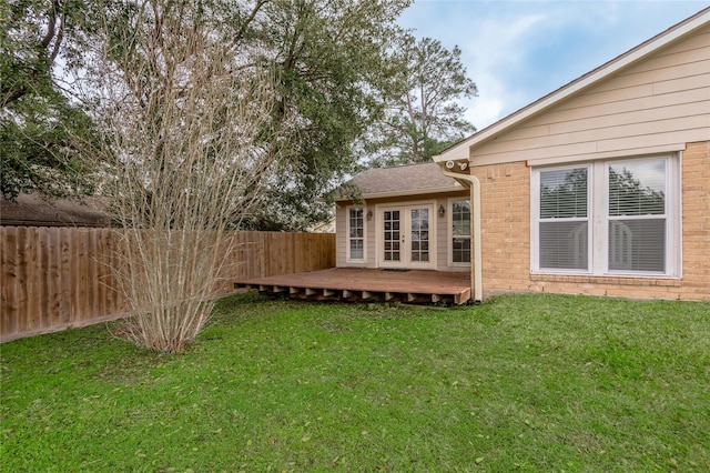 view of yard with french doors, a deck, and a fenced backyard