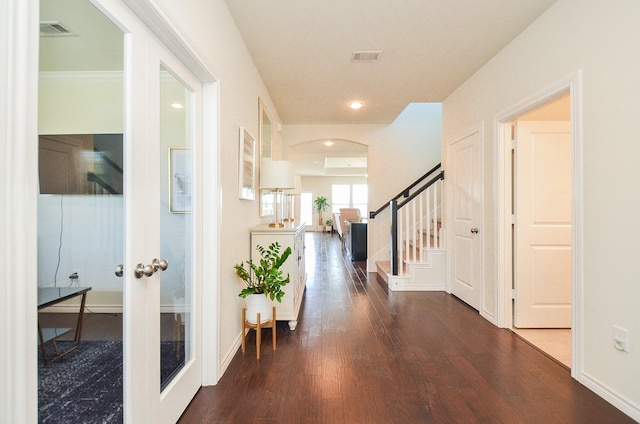 corridor featuring visible vents, wood finished floors, french doors, arched walkways, and stairs