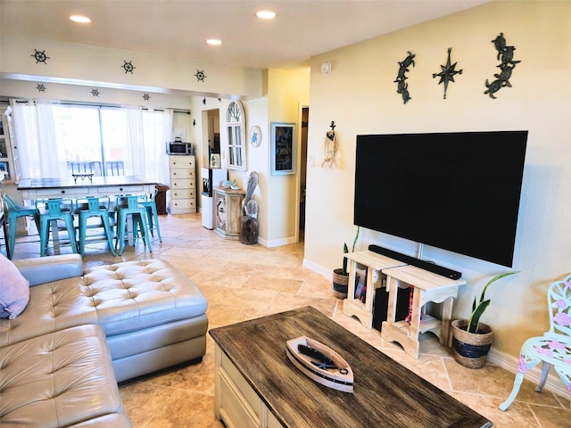 living room featuring stone tile floors, recessed lighting, and baseboards