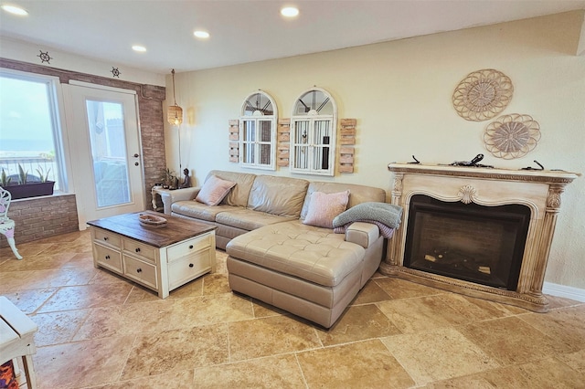 living room with stone finish floor, recessed lighting, a fireplace, and brick wall