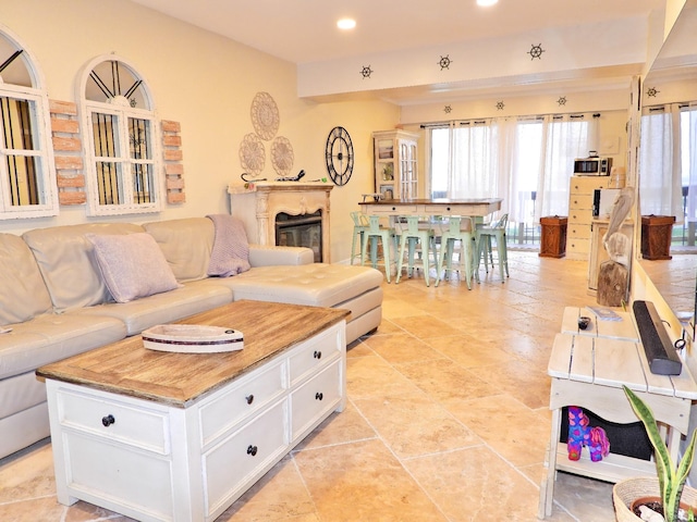 living area featuring a wealth of natural light, a glass covered fireplace, and recessed lighting