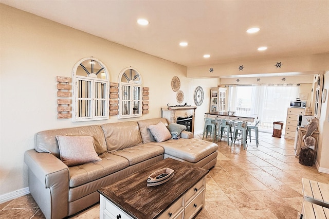 living area featuring a glass covered fireplace, recessed lighting, and baseboards