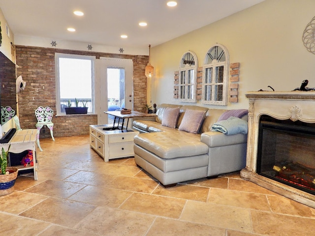 living room with recessed lighting, a fireplace, brick wall, and stone tile flooring