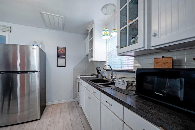 kitchen featuring black microwave, light wood-style flooring, electric range, freestanding refrigerator, and white cabinets