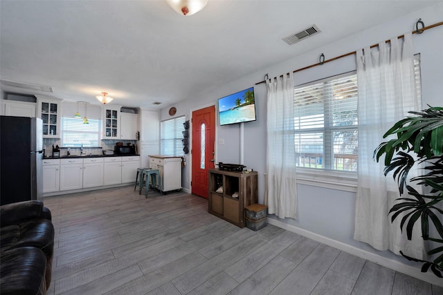 living room with visible vents, light wood-type flooring, and baseboards