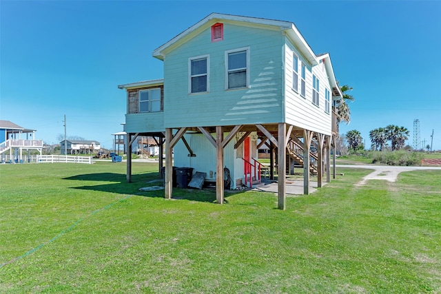 rear view of property with a lawn and stairs