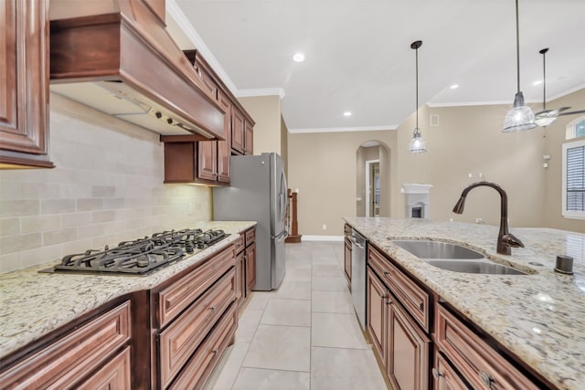 kitchen with premium range hood, a sink, stainless steel appliances, arched walkways, and hanging light fixtures