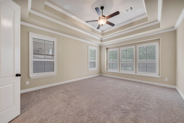 carpeted spare room with baseboards, visible vents, a tray ceiling, ornamental molding, and ceiling fan