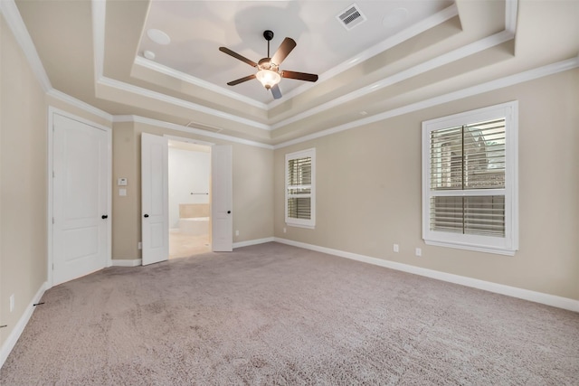 carpeted empty room with a wealth of natural light, visible vents, and a tray ceiling