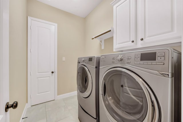 laundry room with light tile patterned floors, baseboards, separate washer and dryer, and cabinet space