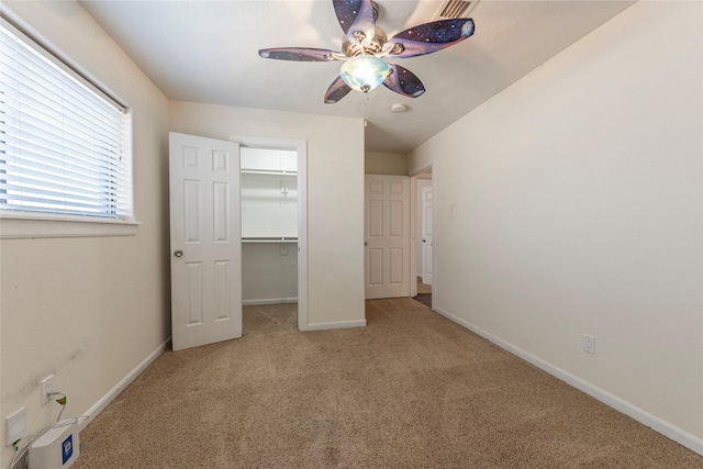 unfurnished bedroom featuring a spacious closet, ceiling fan, baseboards, carpet flooring, and a closet