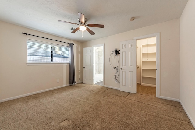 unfurnished bedroom featuring carpet flooring, connected bathroom, a walk in closet, and baseboards