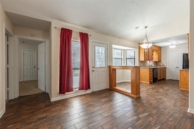 kitchen featuring brown cabinetry, dishwasher, lofted ceiling, and dark wood-style flooring