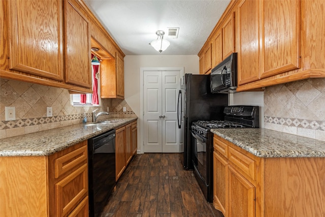 kitchen with visible vents, dark wood finished floors, light stone counters, black appliances, and a sink