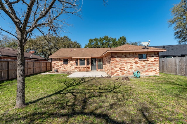 rear view of property featuring brick siding, a fenced backyard, a lawn, and a patio