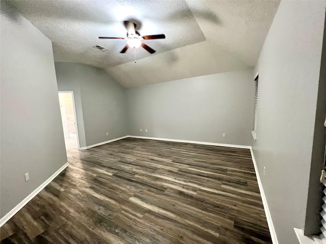 additional living space featuring baseboards, visible vents, lofted ceiling, dark wood-type flooring, and a textured ceiling