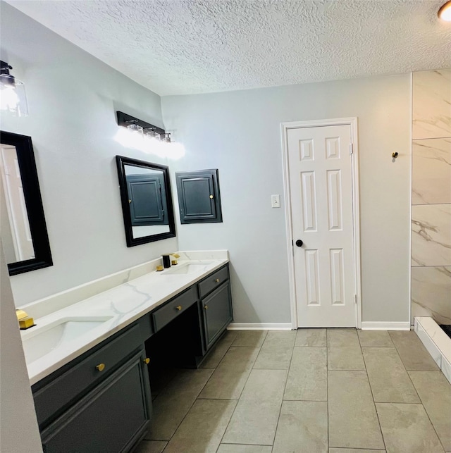 full bathroom with double vanity, baseboards, a textured ceiling, and a sink