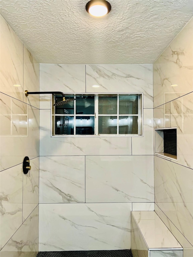 full bathroom featuring a textured ceiling and tiled shower