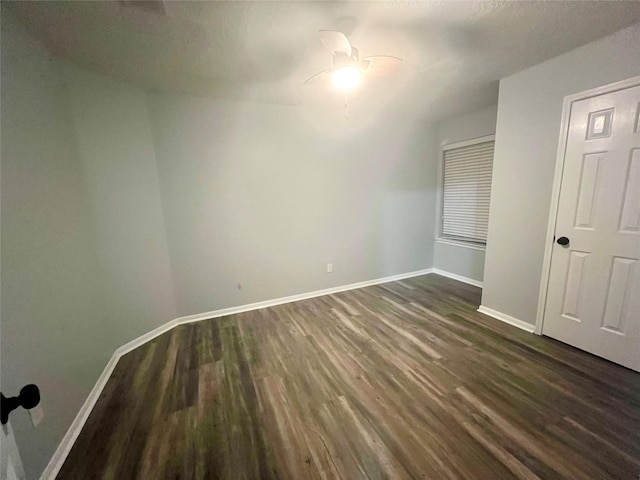 unfurnished bedroom with dark wood-style floors, a ceiling fan, and baseboards