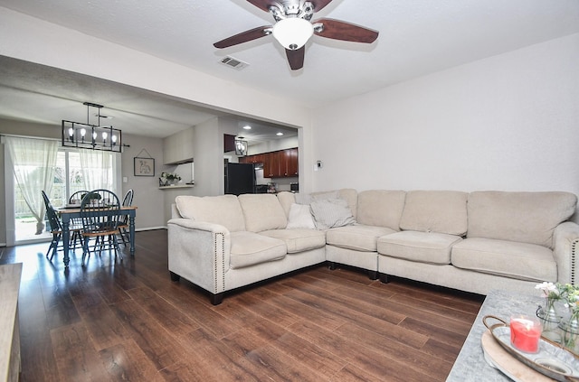 living room featuring dark wood finished floors, ceiling fan with notable chandelier, and visible vents