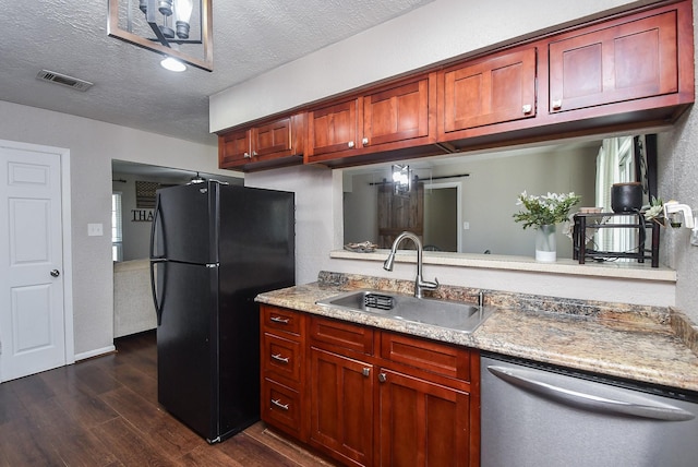 kitchen featuring visible vents, dark wood-style flooring, freestanding refrigerator, a sink, and dishwasher