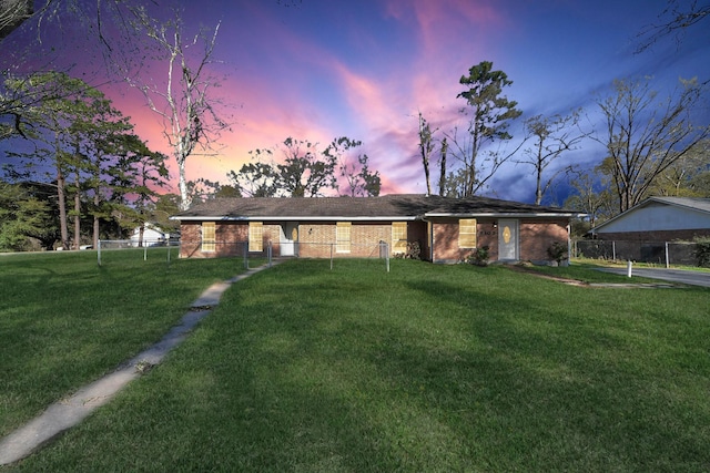 ranch-style house featuring brick siding, a lawn, and fence