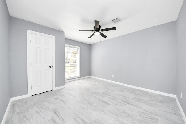 spare room with visible vents, a ceiling fan, and baseboards