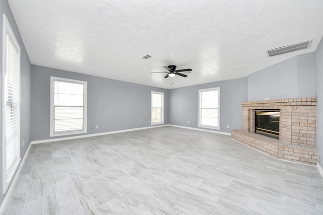 unfurnished living room with visible vents, a fireplace, baseboards, and ceiling fan