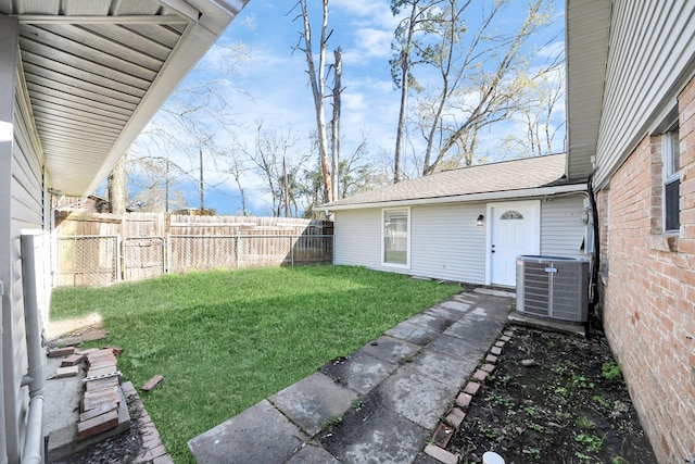 view of yard with central AC and fence