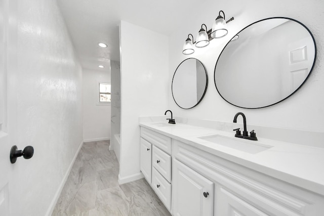 bathroom featuring a sink, baseboards, marble finish floor, and double vanity