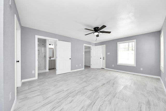 unfurnished bedroom featuring a walk in closet, a ceiling fan, baseboards, and ensuite bathroom