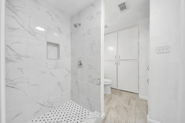 bathroom with toilet, visible vents, and a marble finish shower