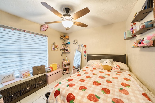 bedroom with ceiling fan, light tile patterned floors, and a textured ceiling