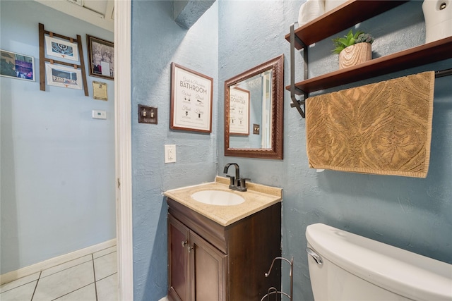 bathroom featuring tile patterned flooring, toilet, vanity, and a textured wall