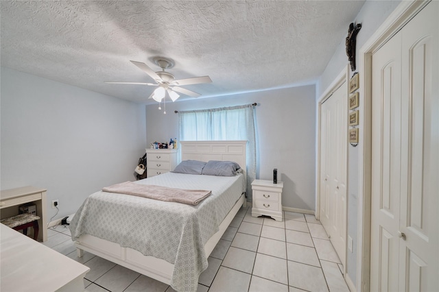 bedroom with baseboards, ceiling fan, light tile patterned floors, a closet, and a textured ceiling