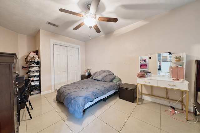 bedroom with a ceiling fan, visible vents, baseboards, light tile patterned flooring, and a closet