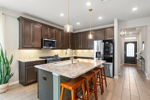 kitchen featuring a sink, stainless steel appliances, tasteful backsplash, and dark brown cabinets