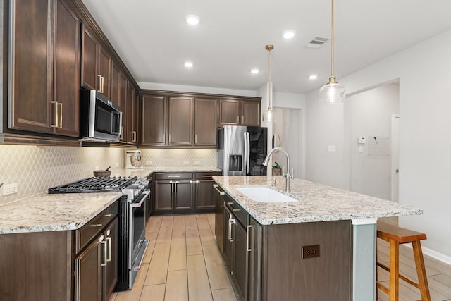 kitchen featuring a sink, stainless steel appliances, dark brown cabinetry, and visible vents