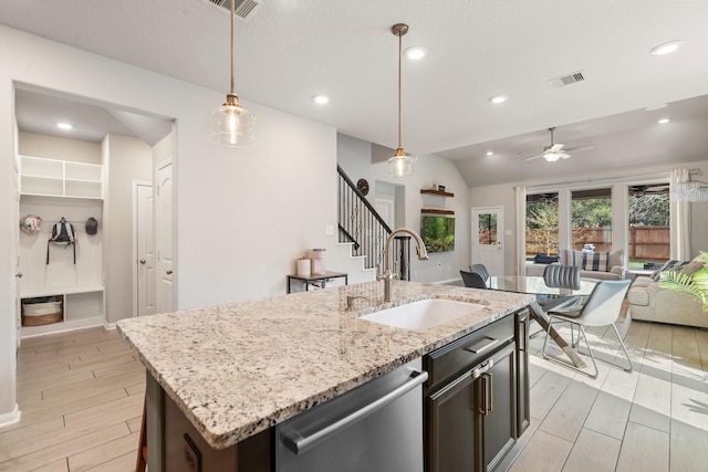 kitchen with visible vents, light wood-style flooring, a sink, stainless steel dishwasher, and open floor plan