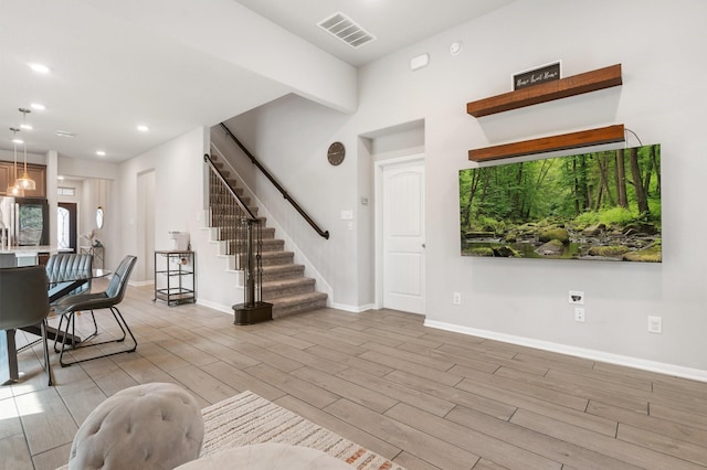 living room featuring wood finish floors, visible vents, recessed lighting, and stairs