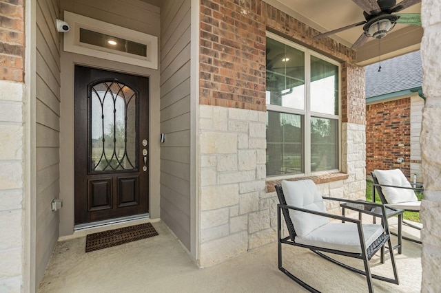 property entrance featuring brick siding, covered porch, and a ceiling fan