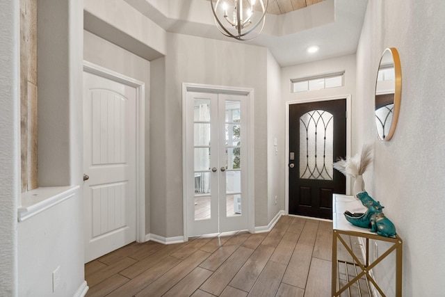 entrance foyer with baseboards, recessed lighting, french doors, an inviting chandelier, and wood finished floors