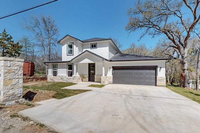 modern farmhouse style home with stone siding, an attached garage, and concrete driveway