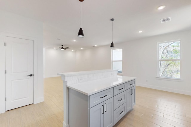 kitchen with visible vents, a kitchen island, recessed lighting, light countertops, and pendant lighting