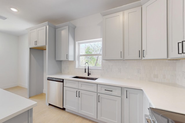 kitchen featuring light wood-style flooring, a sink, backsplash, stainless steel appliances, and light countertops