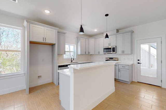 kitchen with backsplash, stainless steel appliances, light countertops, and a sink