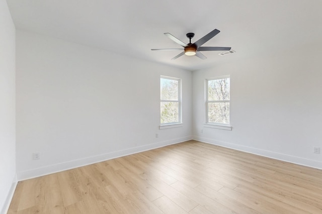 spare room featuring light wood-type flooring, visible vents, baseboards, and a ceiling fan